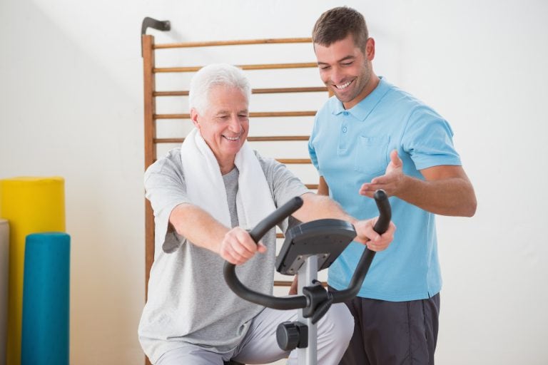 older man strengthen knees with trainer